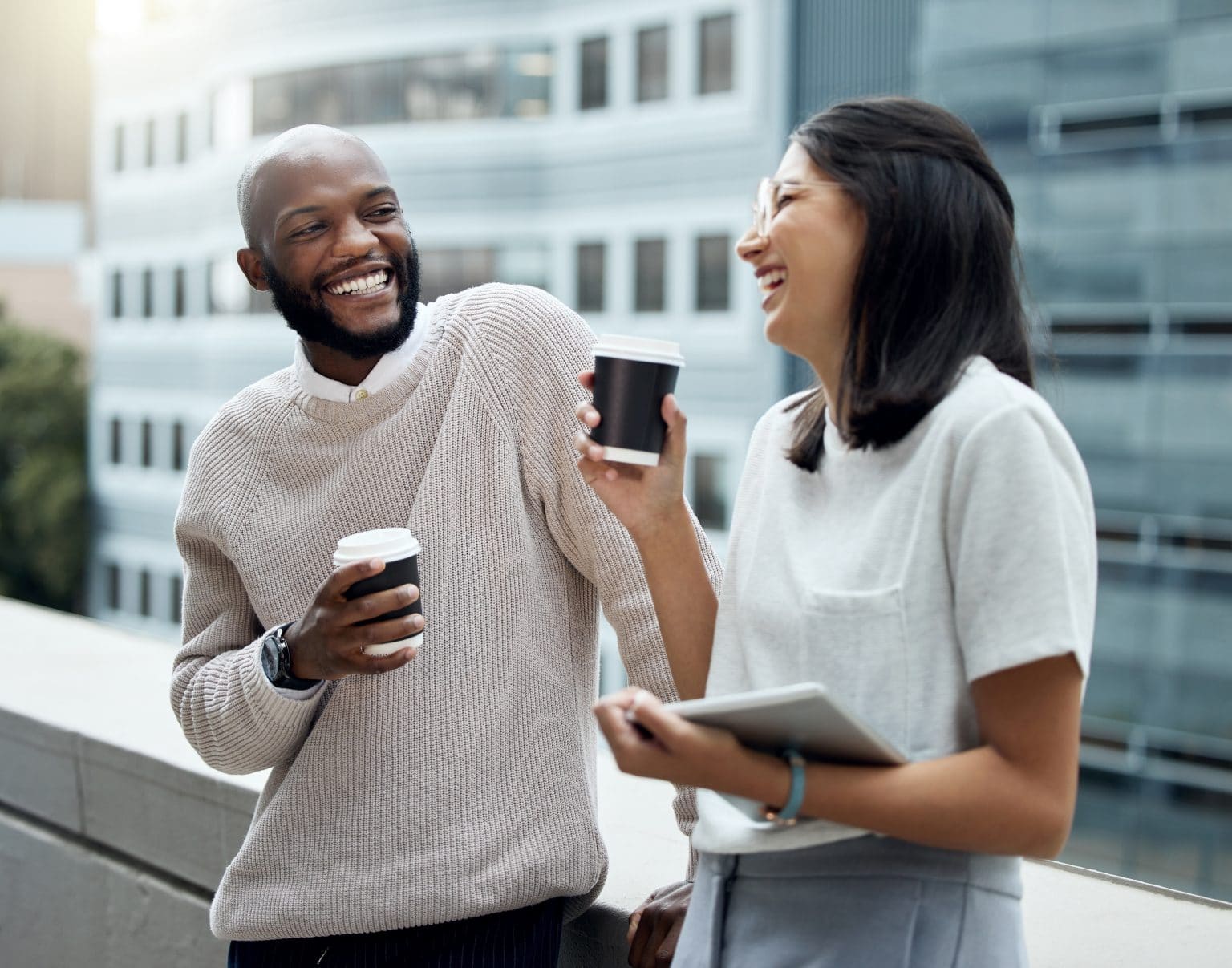 Man and woman on a rooftop lounge area discussing hearing aid financing over coffee