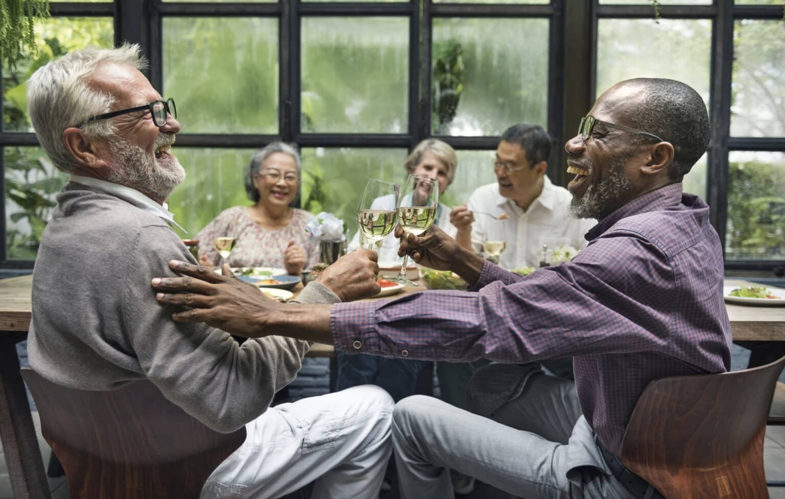 Older friends laughing and having fun at a dinner party.