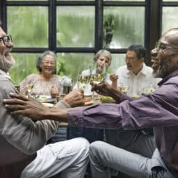Older friends laughing and having fun at a dinner party.