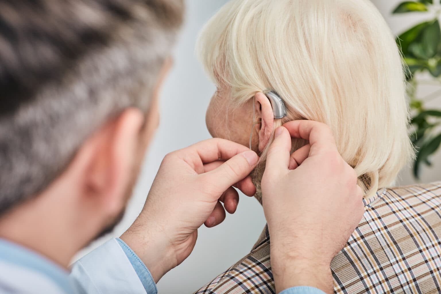 Audiologist fitting a woman with a hearing aid.