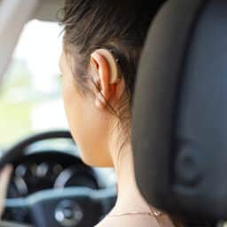 Woman wearing hearing aid while driving