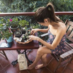 Woman wearing hearing aids fixing succulents on her porch.