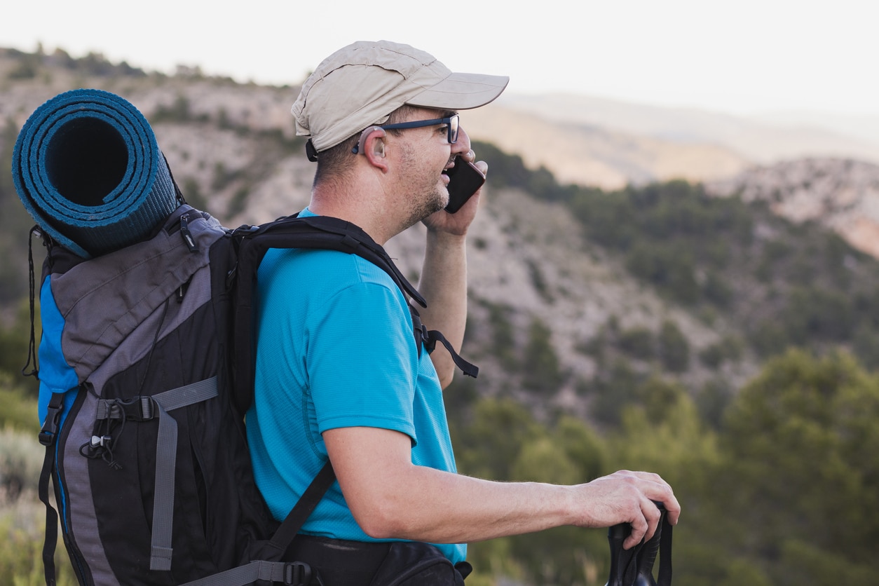 Hiker with hearing aids talking on the phone.