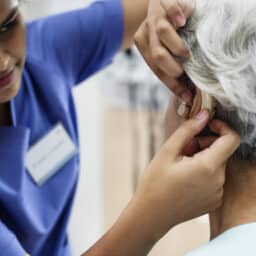 Audiologist adjusting a senior woman's hearing aid