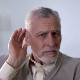 Man with hidden hearing loss struggling to hear a conversation.