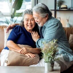 Happy, healthy couple having a discussion about hearing loss in their living room.